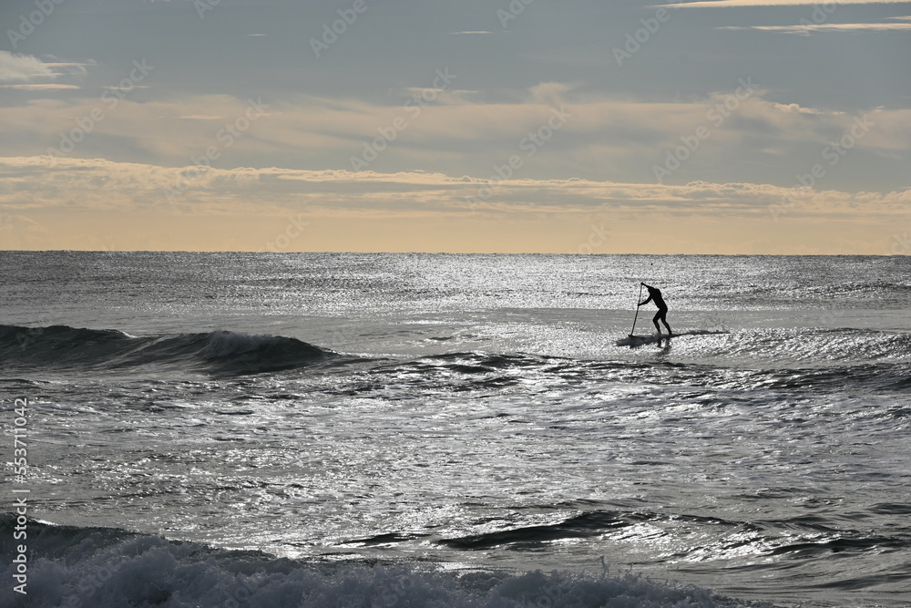 Fototapeta premium Fondo con detalle de persona practicando paddelsurf con cielo azul y naranja de fondo