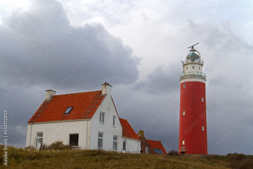 The lighthouse Eierland and some white houses with read tiled roofs in the dunes on the Dutch island Texel in the Wadden sea