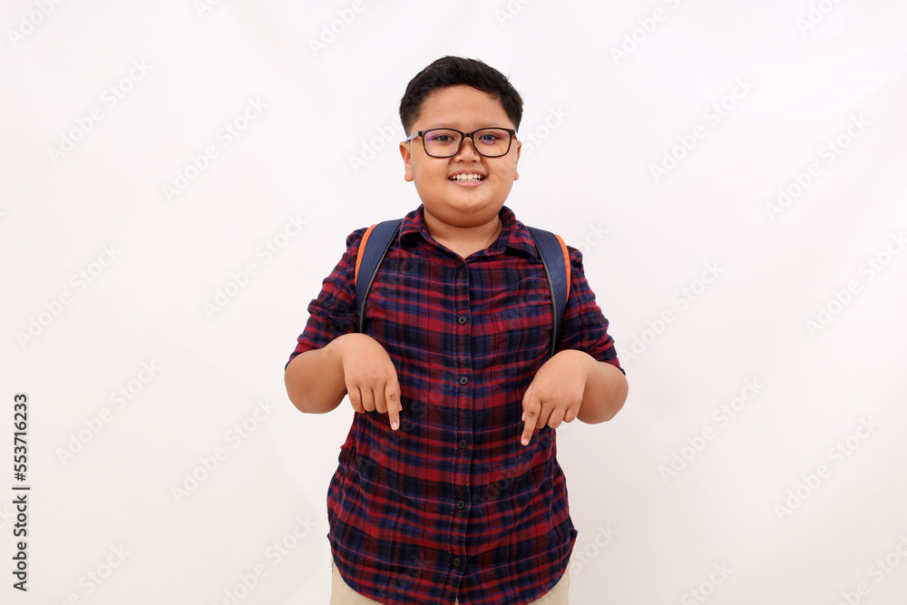Happy asian school boy standing while pointing or presenting below. Isolated on white background Happy asian school boy standing while pointing or presenting below. Isolated on white background