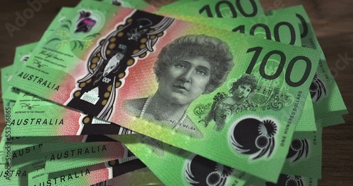 Australian Dollar 100 AUD banknotes falling on the table. Australia currency paper notes count on stack. Timelapse of money counting. 3D concept. photo