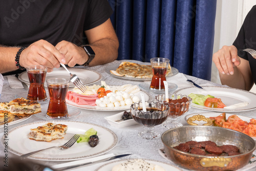 Family breakfast, delicious modern Turkish family breakfast. Beautiful tasty snacks for Sunday morning. Tea in glass. Sausage called sucuk in retro frying pan. Yummy cheese plate. Happy family