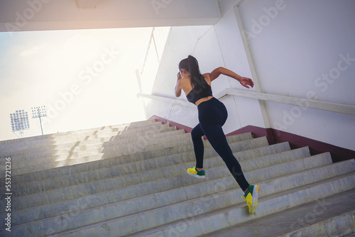 Young woman running sprinting up stairs at stadium. Fit runner fitness runner during outdoor workout. Selected focus © Panumas