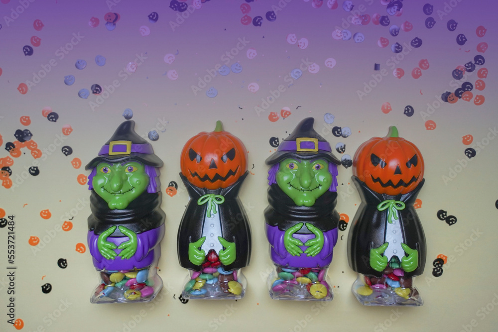 Terrible figures of witches and monsters on violet background strewn with colorful confetti. The concept of the terrible Halloween holiday. Festive figurines. Empty space.