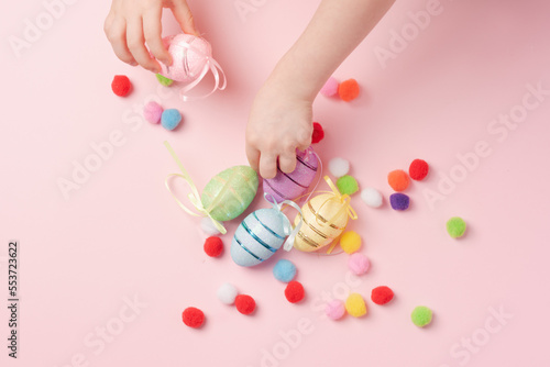 Children s hands collect Easter eggs on a pink background. Decorative eggs and fluffy balls on a pink background.