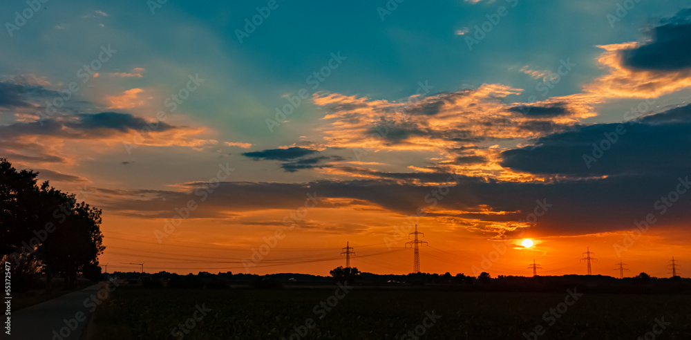 Naklejka premium Beautiful sunset with a dramatic sky and overland high voltage lines near Tabertshausen, Bavaria, Germany