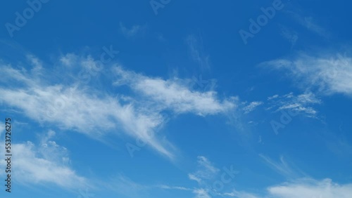 Wispy cirrus clouds pass over blue sky in nature. Elongated cirrus clouds move across sky. Time lapse. photo