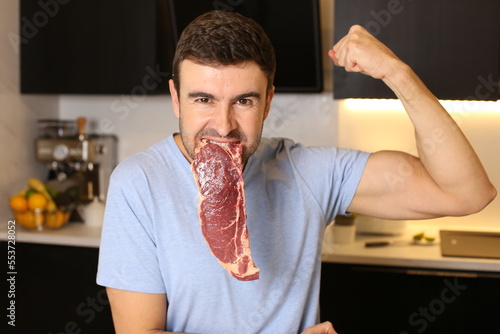 Muscular man eating beef and flexing biceps 