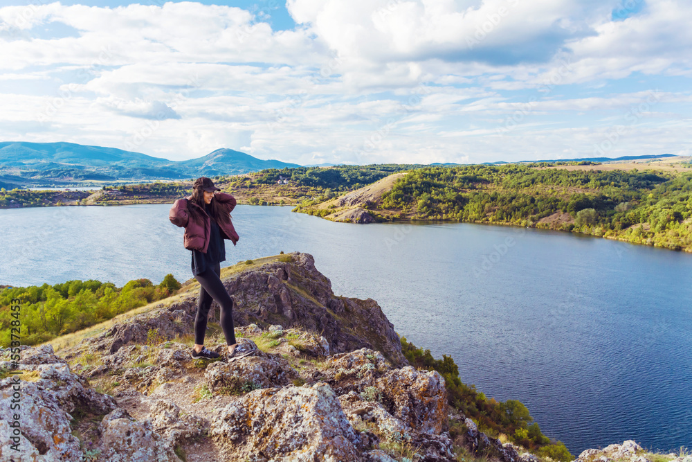 Traveler woman walking on a rocks  high above a blue lake .Traveling in the autumn  nature in Bulgaria	. Pchelina Lake 