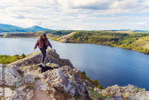 Traveler woman walking on a rocks  high above a blue lake .Traveling in the autumn  nature in Bulgaria	. Pchelina Lake  photo