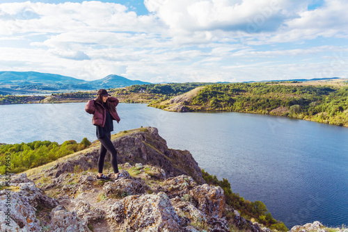 Traveler woman walking on a rocks high above a blue lake .Traveling in the autumn nature in Bulgaria . Pchelina Lake 