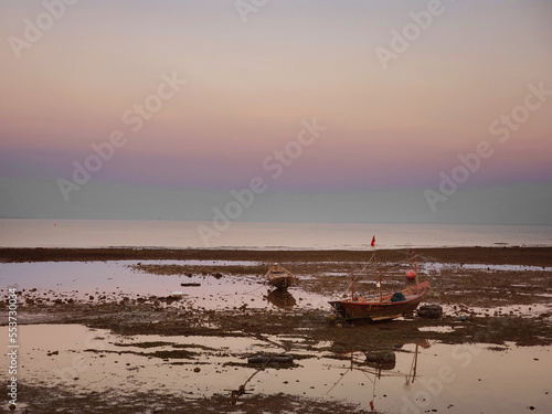 Fall of sea levels at sunset with fish boats tides