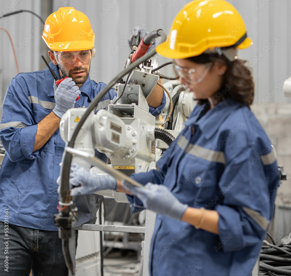 Industrial engineer working on robot arm maintenance in modern technology factory. Technician checking robotic automated welding torch machine to control welding process. Innovative engineering. Industrial engineer working on robot arm maintenance in modern technology factory. Technician checking robotic automated welding torch machine to control welding process. Innovative engineering.