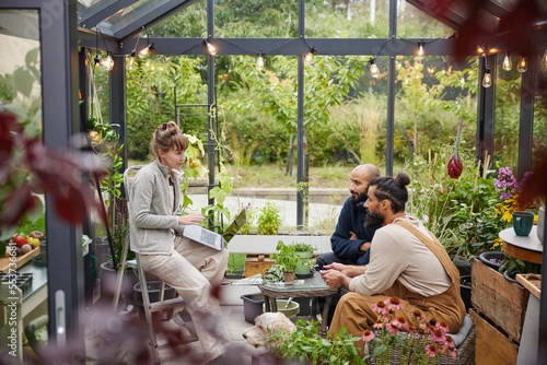 Smiling friends talking in greenhouse photo