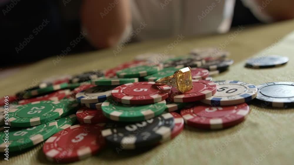 A woman's hand places an engagement ring on the playing chips . Gambling, putting all your money on the line A woman's hand places an engagement ring on the playing chips . Gambling, putting all your money on the line