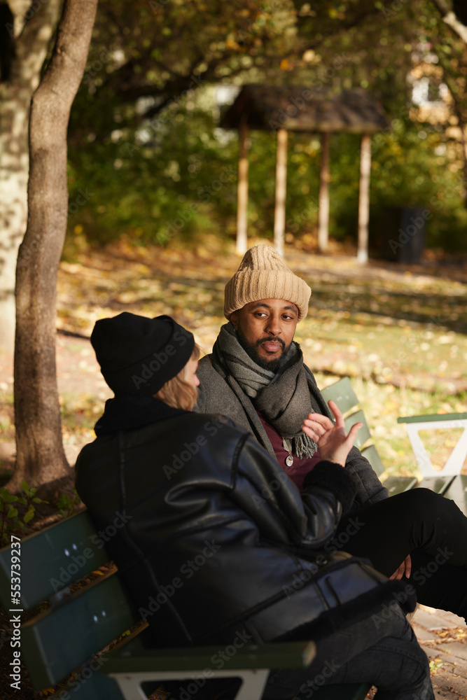 Smiling man talking to friend on bench Smiling man talking to friend on bench