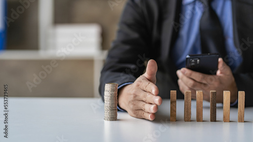 Businessman stops her hand blocking or falling dominoes Financial business and risk management Businessman prevents wooden blocks from falling with his hands