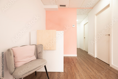 Hallway of a beauty salon with booths to apply treatments and gray velvet armchair