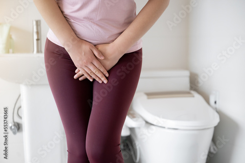 Fototapeta A woman wearing leggings is complaining of pain from urinary incontinence in fro