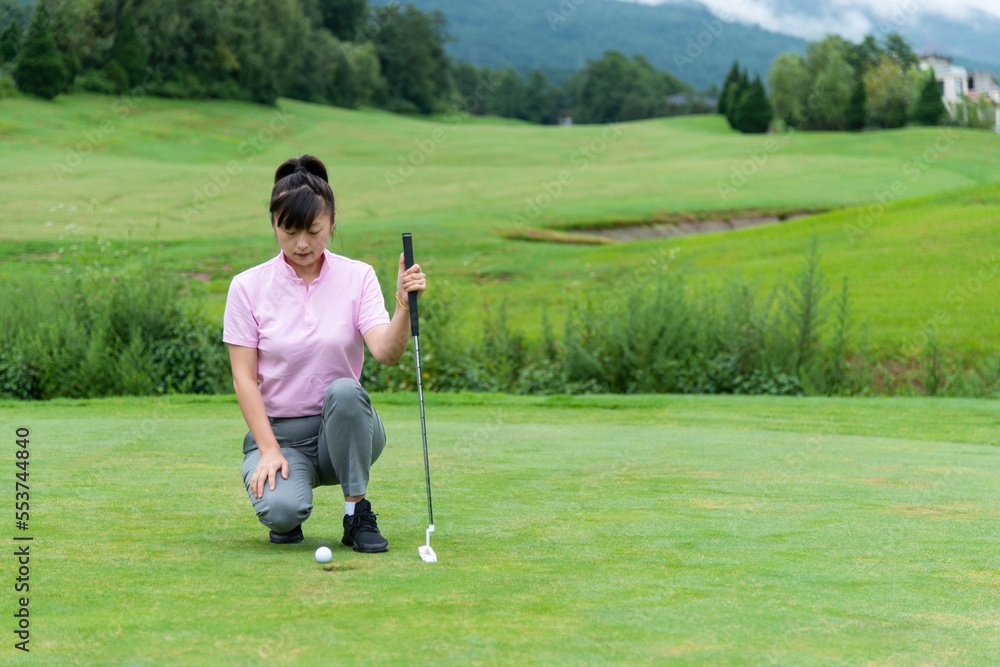 Fototapeta premium Female golfer crouching looking the golf ball