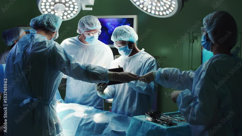 Group of surgeons performing operation in hospital using tablet and ...