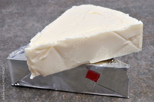 Portions de fromage à tartiner dont une ouvert en gros plan sur fond gris photo