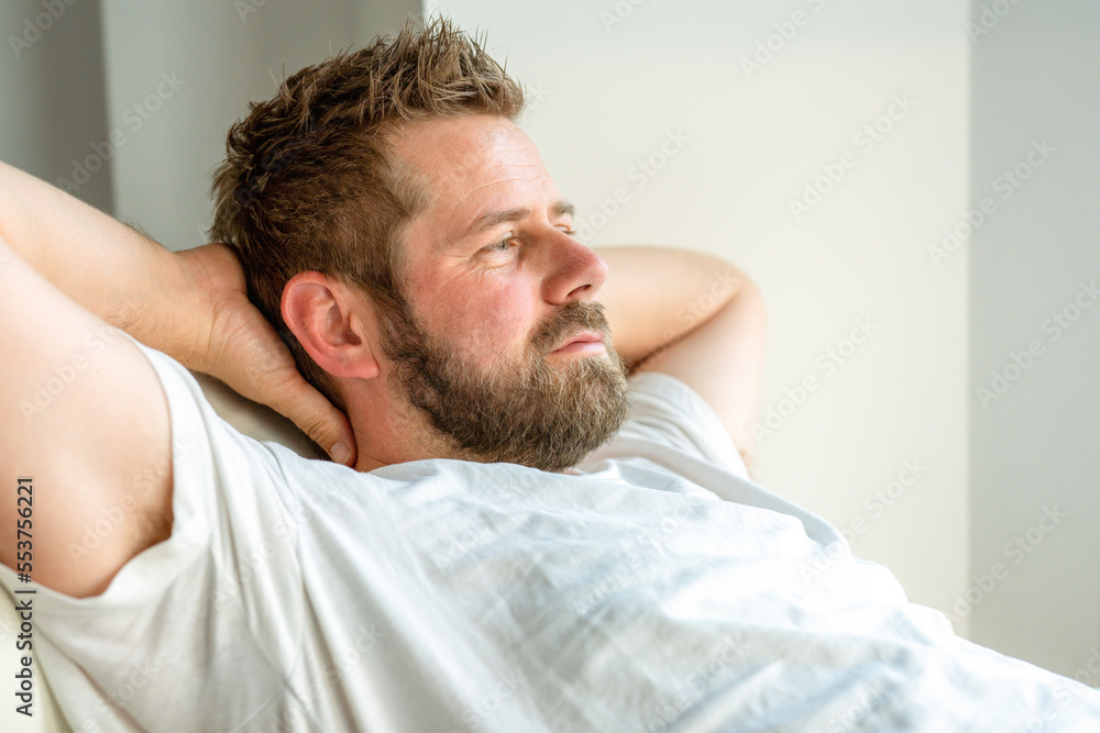 Fototapeta premium Portrait of a casual tired man resting sitting on a couch at home