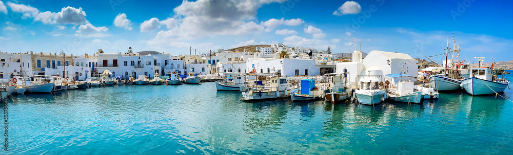 Naoussa village with mooring boats and cafe tables, panorama web format, toned