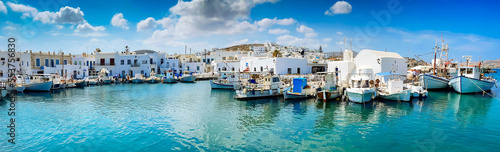 Naoussa village with mooring boats and cafe tables, panorama web format, toned