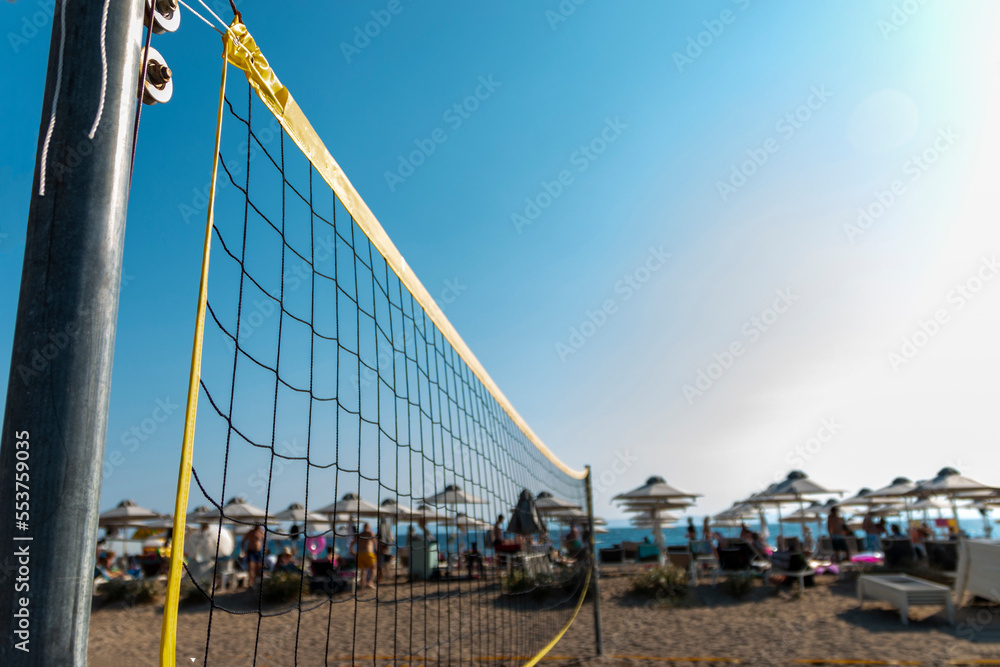 Fototapeta premium Volleyball net on sand in summer background. Outdoor leisure games. Active lifestyle on beach with sand near sea or ocean with sky.