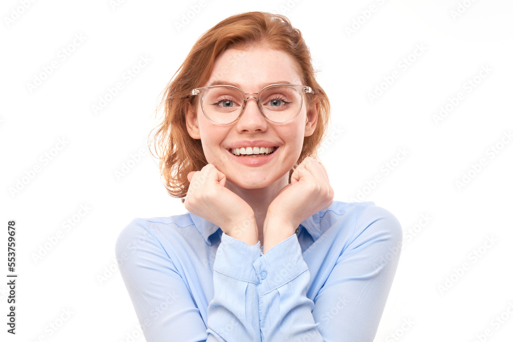 Portrait of attractive red-haired girl in business shirt and glasses smiling joyfully isolated on white studio background.