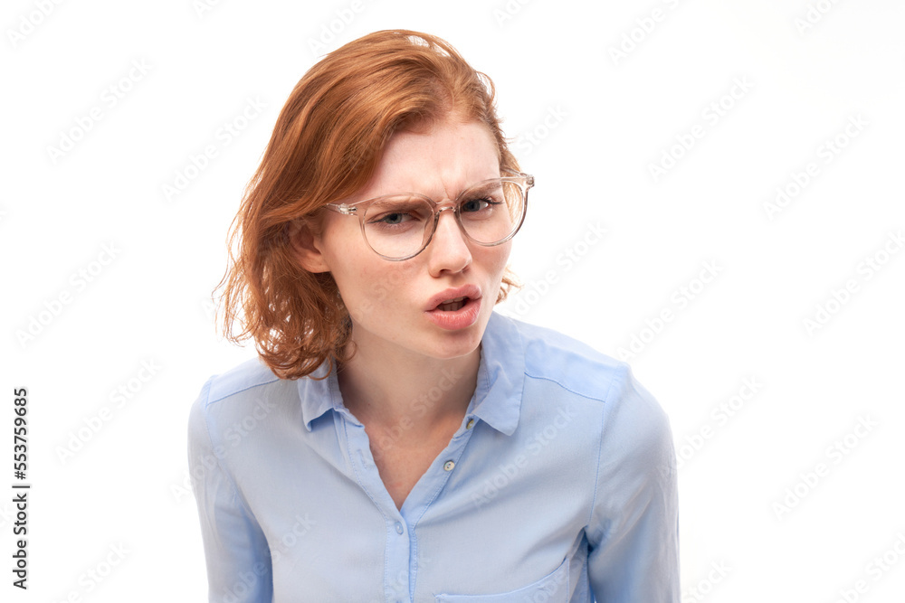 Redhead young woman wearing glasses squinting while looking at camera isolated on white background. Vision problems concept
