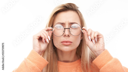 Blonde young woman wearing glasses squinting while looking at camera isolated on white background. Vision problems concept photo