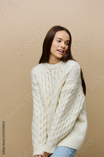 a modest woman stands full-face on a light background in a white sweater, looking down with embarrassment, slightly hunched over with her hands down