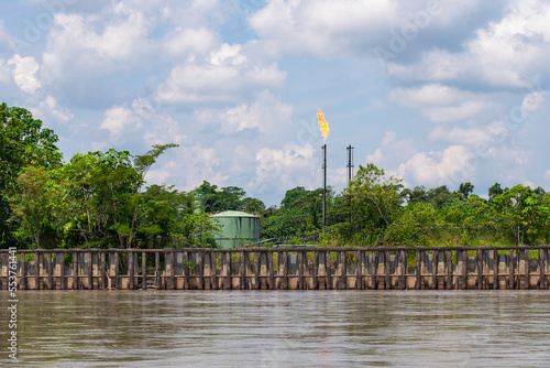 Oil extraction site with chimney for burning of combustion gases and storage tank along Napo river, Amazon rainforest, Ecuador.  photo