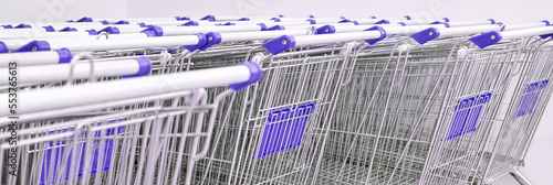 Many same shop trolley. Retail consumer carts. Empty parking store mall. Outside silver basket stock. Metal supermarket wheel.