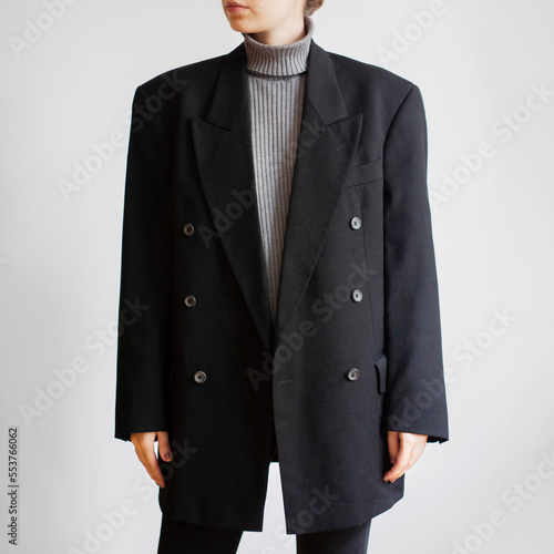 Woman wearing gray turtleneck, oversized blazer and black jeans isolated on white background