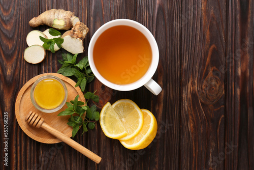Flat lay composition of tea with mint, honey, lemon and ginger on wooden table. Space for text