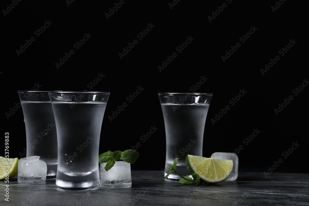 Shot glasses of vodka with lime slices, ice and mint on grey table - obrazy, fototapety, plakaty 