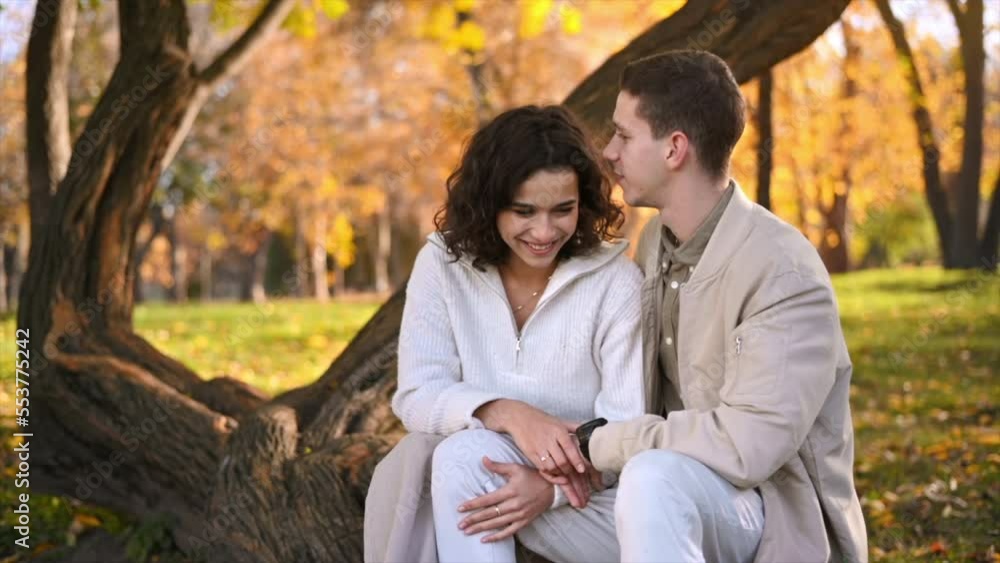 A romantic couple in an autumn park. Man kissing his woman. Autumn atmosphere, yellowed trees and leaves around. Slow motion A romantic couple in an autumn park. Man kissing his woman. Autumn atmosphere, yellowed trees and leaves around. Slow motion