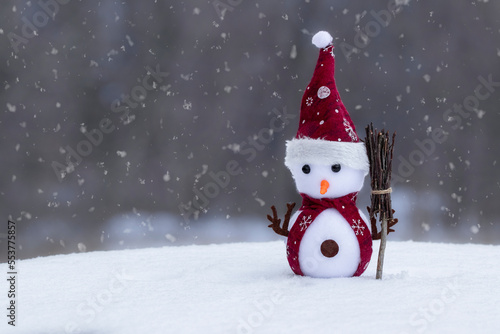 Festive Christmas background with snowman on the snow.Funny snowman in santa hat with broom on snow.Winter concept.