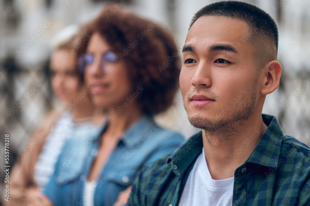 Obraz premium Cute pensive young man in the company of women