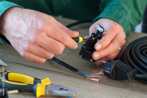 An electrician handyman using small screwdriver fixing an electric wire plug.