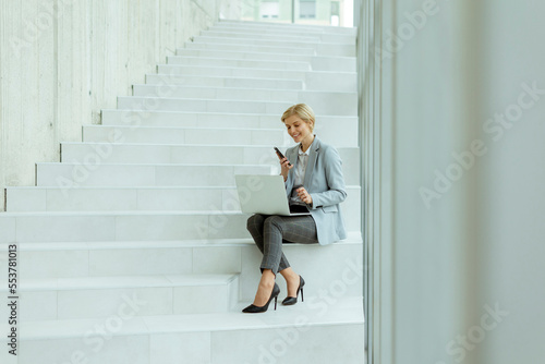Businesswoman using mobile phone on modern office stairs © BGStock72