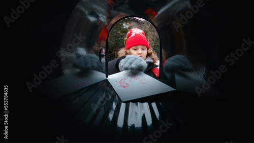 POV Cute little kid boy puts a letter with his Christmas wishes addressed to Santa Claus, Notrh Pole into the mailbox