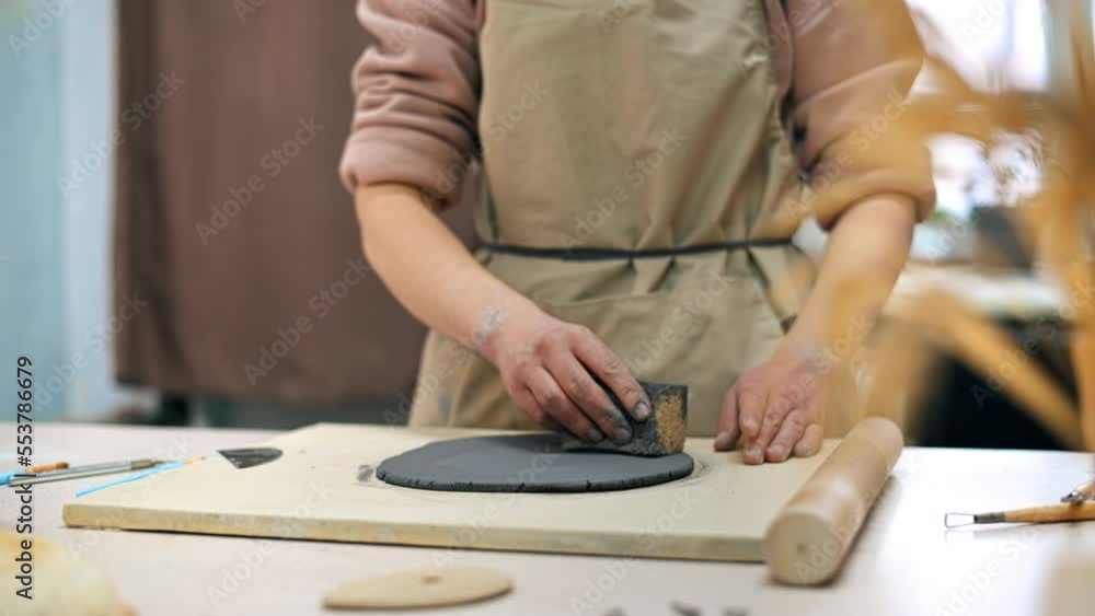 The master of sculpting pottery working in a studio. Smoothing clay. Tools and materials on the table The master of sculpting pottery working in a studio. Smoothing clay. Tools and materials on the table