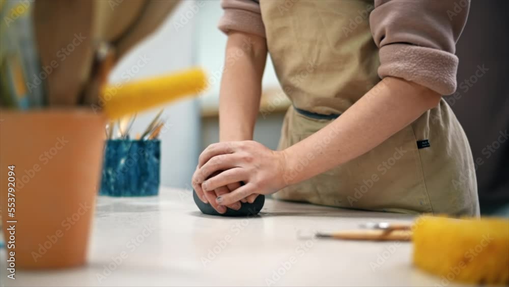 The master of sculpting pottery working in a studio. Kneading a piece of clay with her hands. Tools on the table. Slow motion The master of sculpting pottery working in a studio. Kneading a piece of clay with her hands. Tools on the table. Slow motion