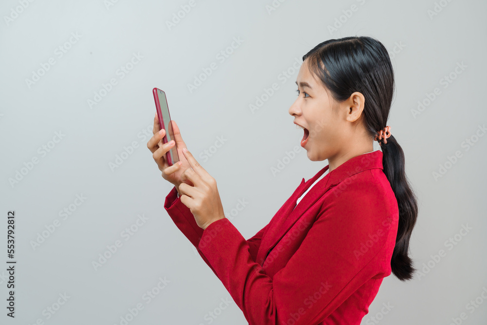 Naklejka premium Pretty lovely manager lady successful business asian women in red suit isolated over background. Holding and using mobile smartphone or cellphone