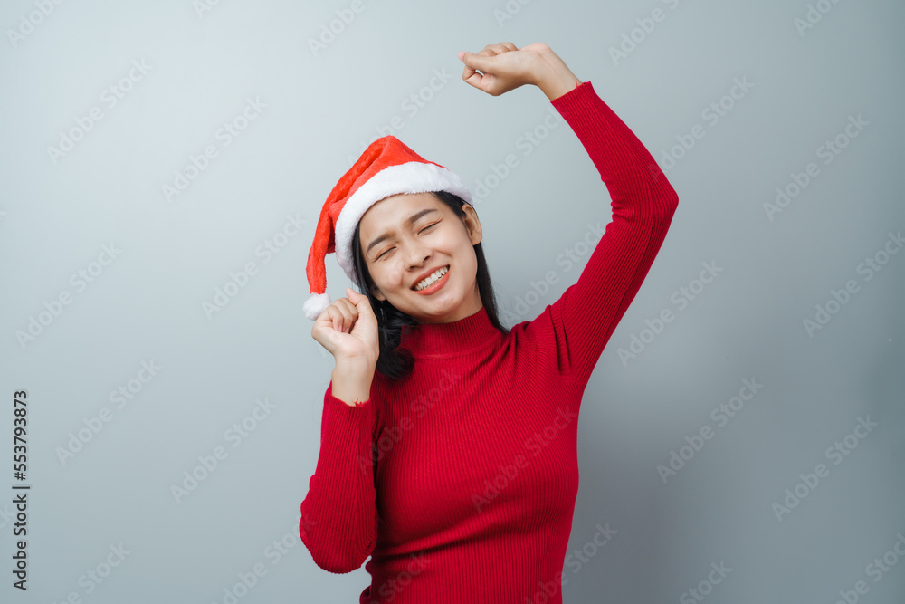 Pretty lovely lady asian thai women in red sweater and santa christmas hat isolated over grey background. dancing Pretty lovely lady asian thai women in red sweater and santa christmas hat isolated over grey background. dancing
