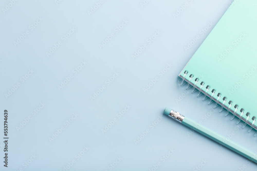 Blue notepad and pencil on a blue background. Place for your text Blue notepad and pencil on a blue background. Place for your text