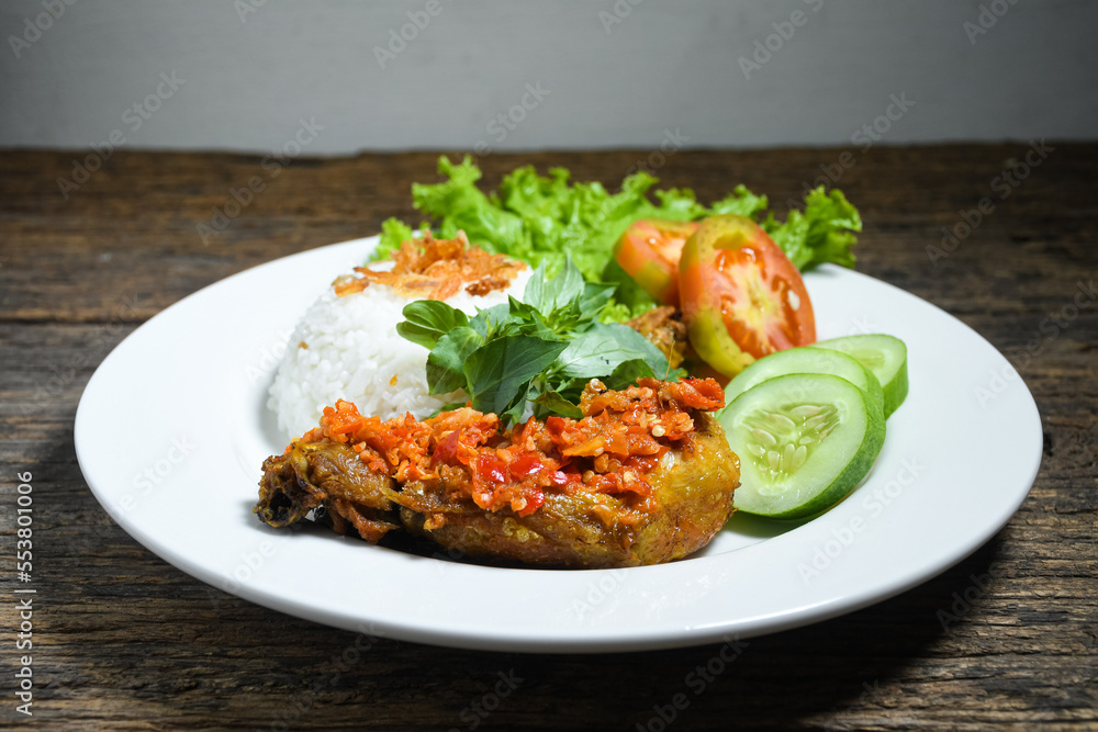 Ayam geprek sambal indonesian food or geprek fried chicken with sambal hot chili sauce served steam rice on white plate Ayam geprek sambal indonesian food or geprek fried chicken with sambal hot chili sauce served steam rice on white plate